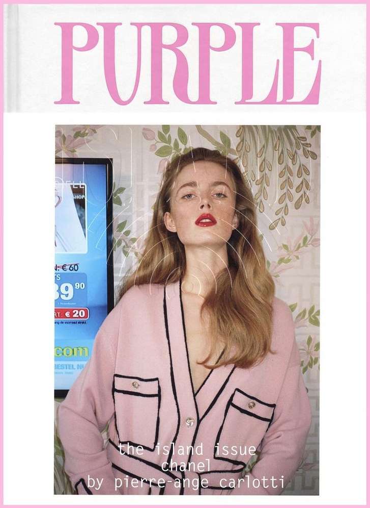 Magazine cover featuring a young woman with red lipstick, wearing a pink cardigan, with a television and floral wallpaper in the background.