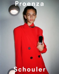 Model wearing a vibrant red double-breasted blazer and metallic choker against a grey concrete wall in Paris