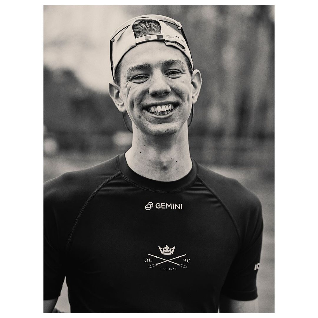 Portrait of a smiling young man wearing a cycling cap and dark athletic jersey, photographed by Pieter Hugo in Cape Town.