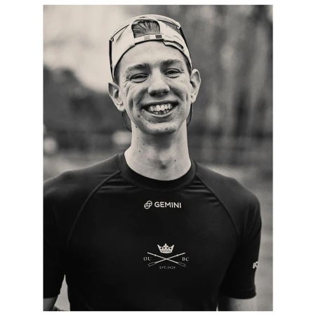 Portrait of a smiling young man wearing a cycling cap and dark athletic jersey, photographed by Pieter Hugo in Cape Town.