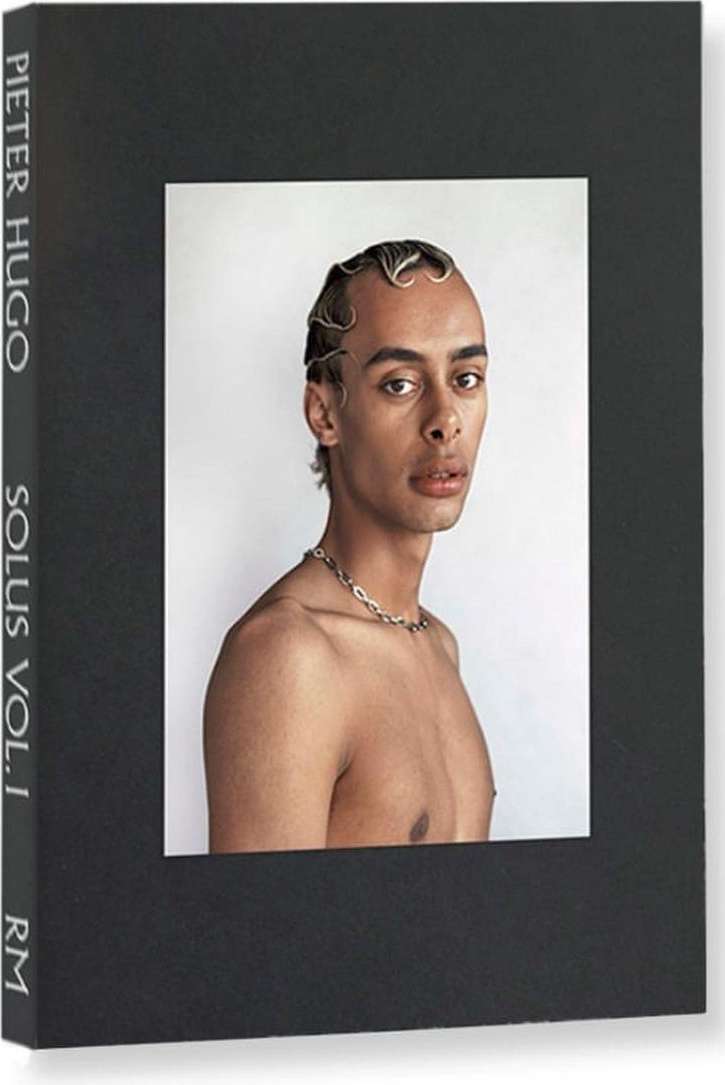 Book cover featuring a portrait of a bare-chested person with stylized hair and a silver chain against a stark white background.
