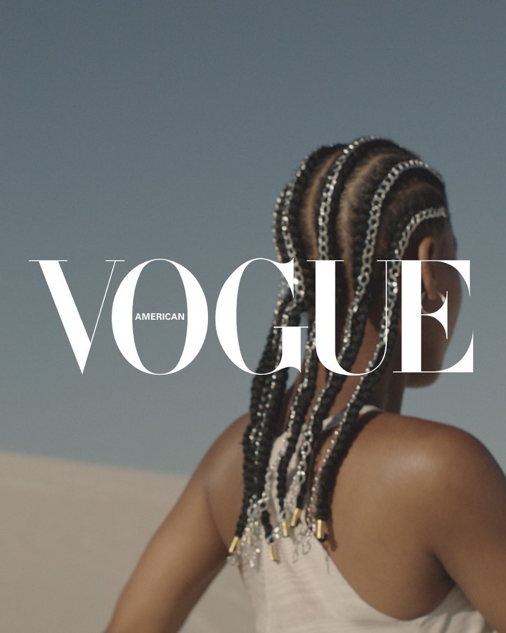 Fashion magazine cover featuring an adult woman with braids, wearing a neutral top, against a clear sky and sandy background.