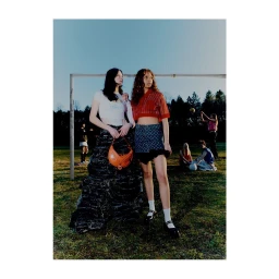Two young female models posing outdoors on grass near a goalpost, photographed by Pietro Groff.