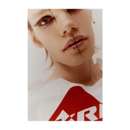 Close-up portrait of a model with dramatic black eyeliner, glossy lips, and glitter makeup wearing a white t-shirt by photographer Pietro Groff