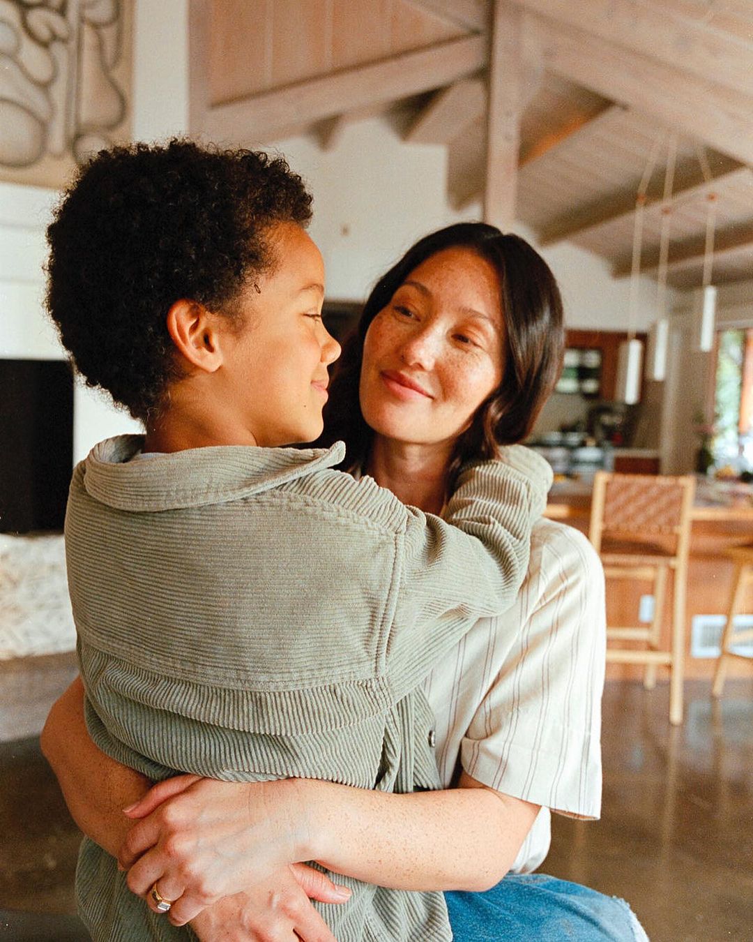 Warm embrace between mother and child indoors, showcasing a heartfelt connection in a cozy, well-lit home environment.