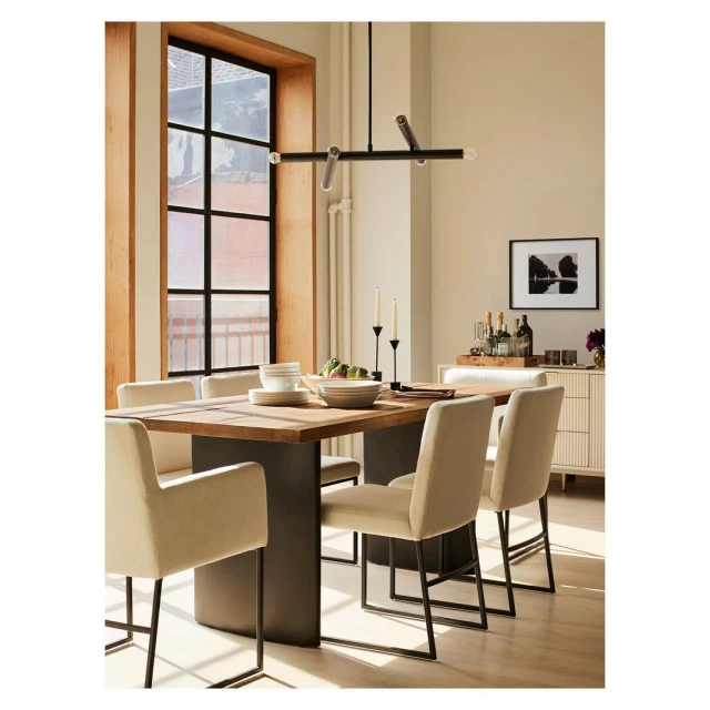 Contemporary dining room interior featuring a wooden table, upholstered chairs, modern chandelier, and window with natural light.