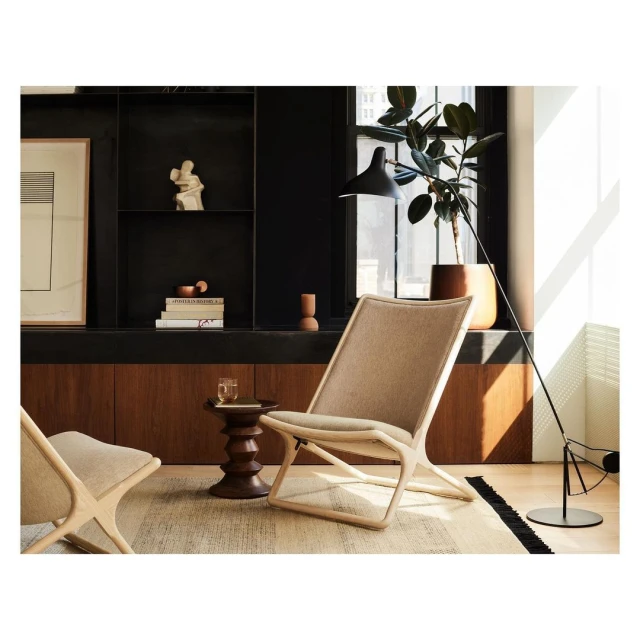 Interior design featuring two light beige lounge chairs, dark wood side table with a glass, and a floor lamp in a modern room.