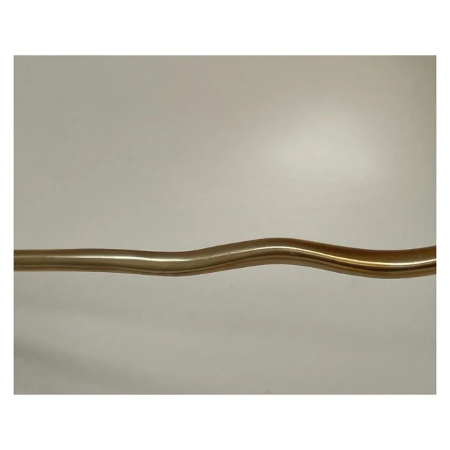 Abstract studio shot of a curved brass tube against an off-white background, with a simple, modern aesthetic, and soft lighting.
