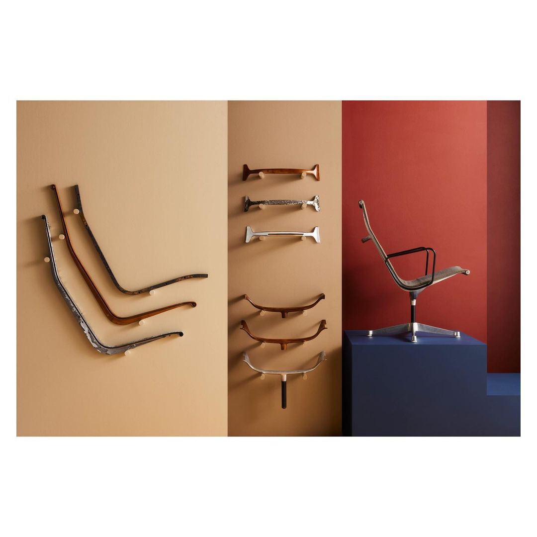 Arrangement of modern chairs including chair parts mounted on a wall in an interior setting with contrasting wall colors.