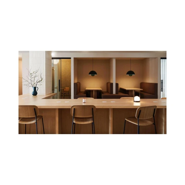 A contemporary coffee shop with light wood chairs and table, booth seating, and hanging pendant lights in a neutral color palette.