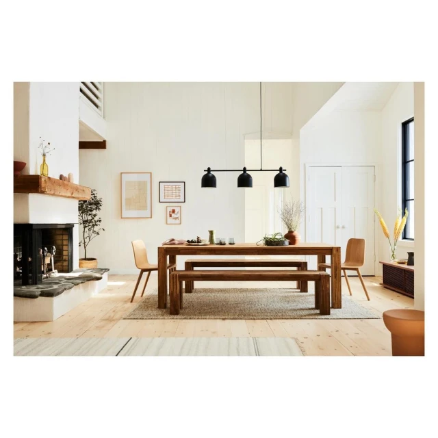 Interior of a living and dining space with a wood table and bench seating, light wood floors, a fireplace, and neutral tones.