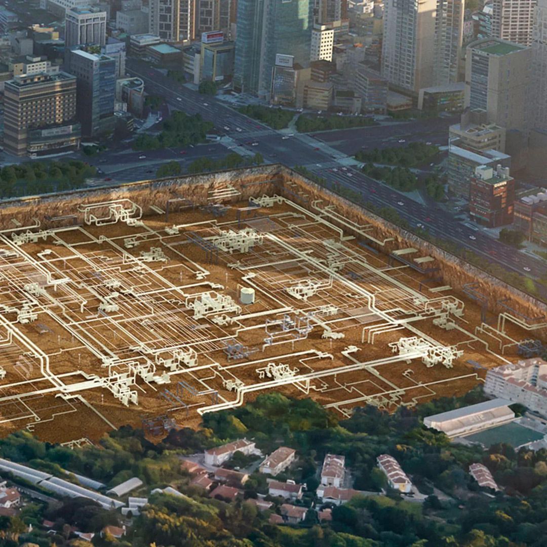 Architectural CGI rendering showing underground piping network beneath city street with buildings and foliage. Aerial, eye-level perspective.