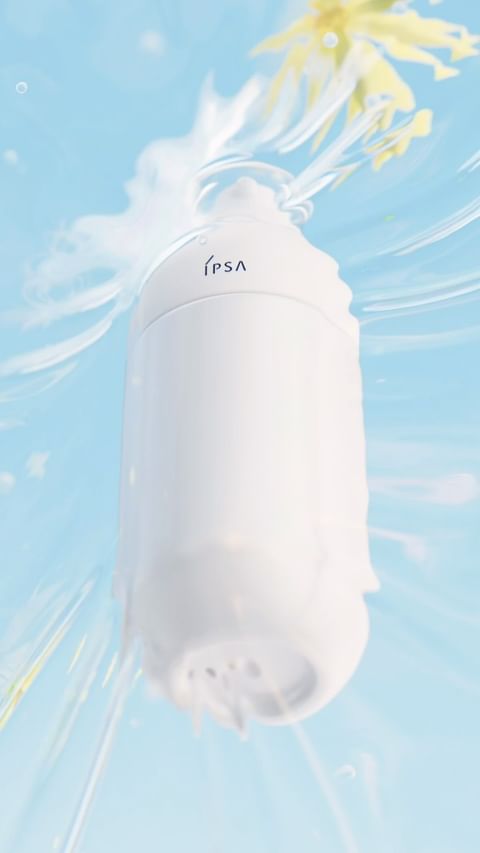 White bottle of beauty serum with IPSA branding under water with soft lighting and flowers in a studio setting.