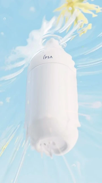 White bottle of beauty serum with IPSA branding under water with soft lighting and flowers in a studio setting.