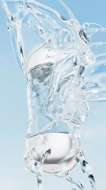 Product shot of a clear glass IPSA bottle filled with water and surrounded by splashing water against a light blue background.
