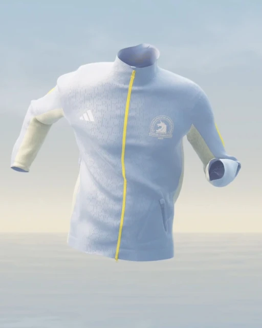 Light blue Adidas jacket with yellow trim and Boston Marathon logo floating in a soft-focus blue, white, and tan neutral environment.