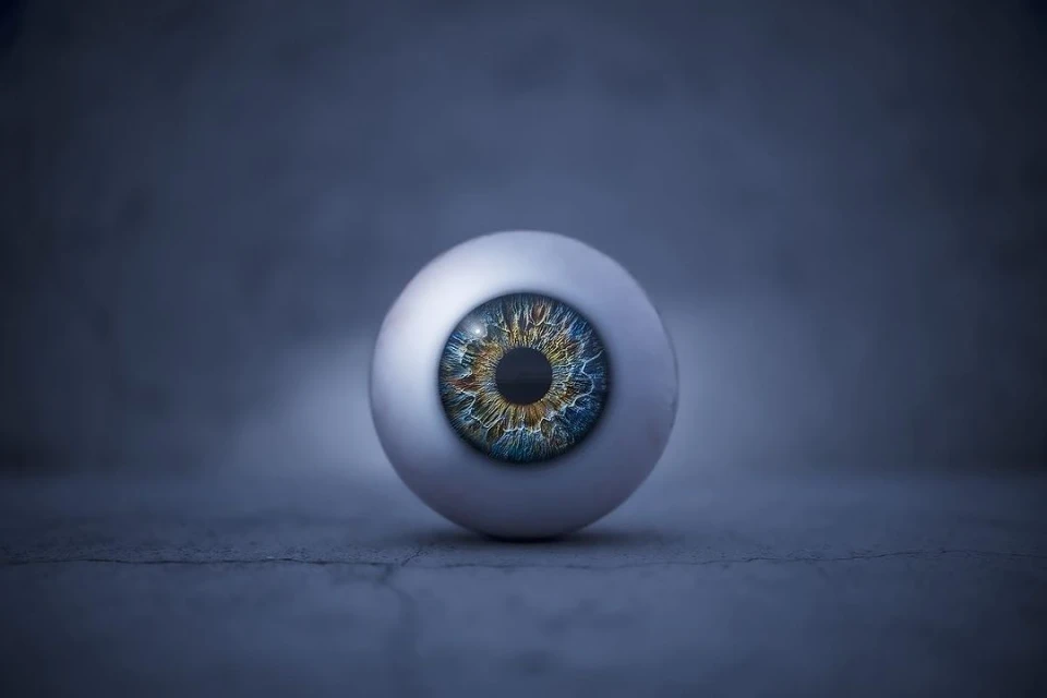 Close-up studio shot of a realistic prosthetic eye with a multicolored iris against a dark background, creating a visually striking image.