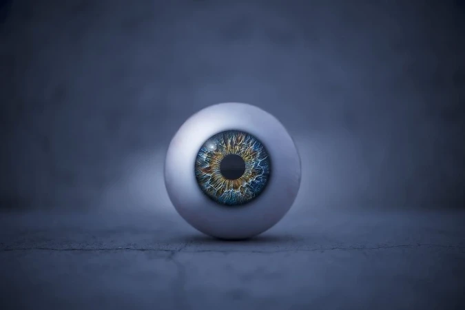 Close-up studio shot of a realistic prosthetic eye with a multicolored iris against a dark background, creating a visually striking image.