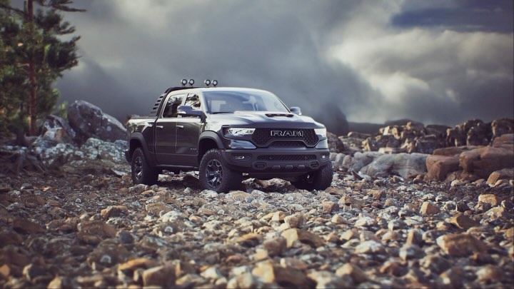 Dark gray Ram TRX pickup truck on a rocky terrain with cloudy skies in the background, captured in a medium shot.