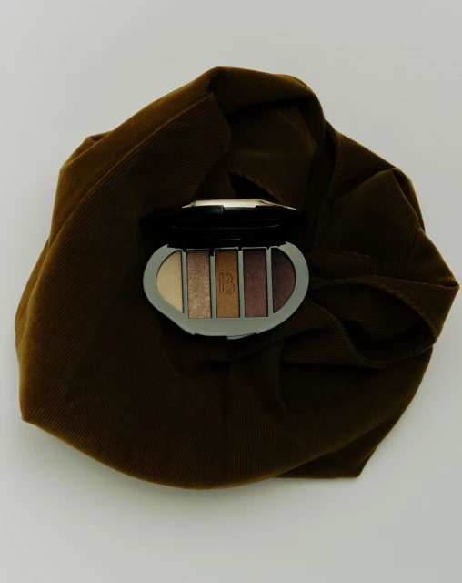 Makeup palette on a brown wrinkled cloth. Earth tones, close-up studio shot for beauty or cosmetic brand marketing.