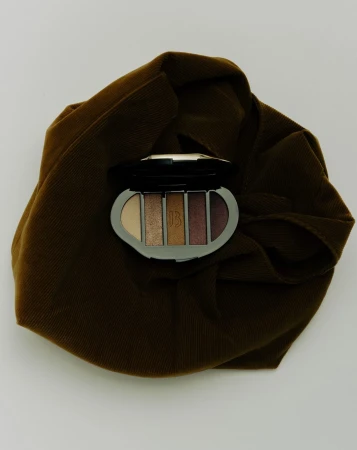 Makeup palette on a brown wrinkled cloth. Earth tones, close-up studio shot for beauty or cosmetic brand marketing.