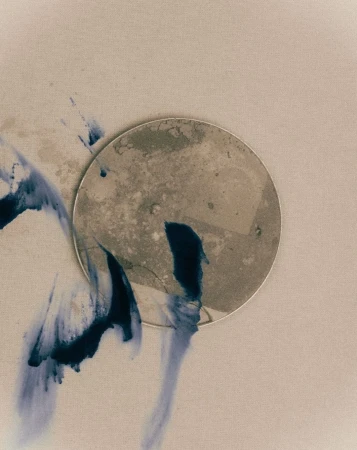 Abstract art featuring a textured circular shape with indigo-colored ink washes against a neutral background, in a conceptual style.