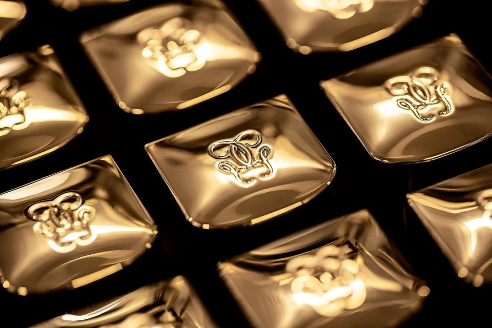 Closeup of multiple gold cosmetic compacts with an elegant logo on a black background. Beauty and luxury concept.