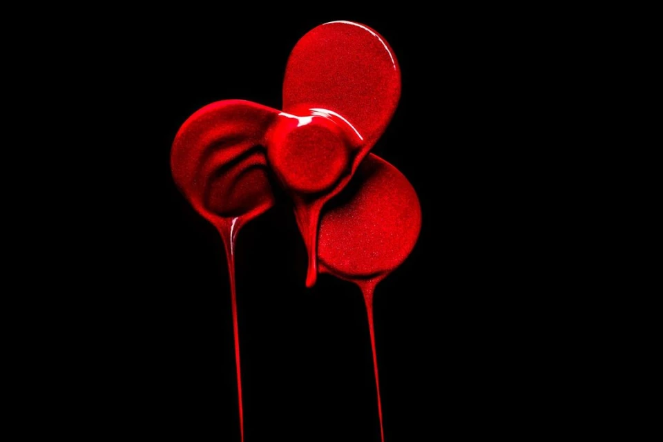 Abstract close-up of three circular pools of glossy, saturated red liquid with rivulets dripping against a stark black background.
