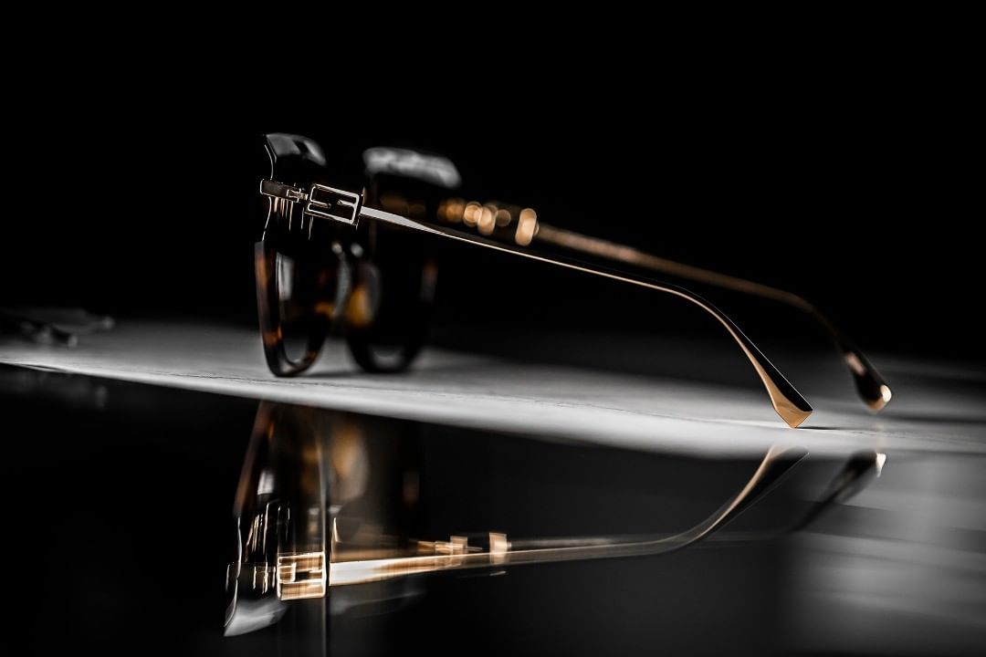 Elegant tortoiseshell eyeglasses on a glossy surface with a dark background, showcasing fashion eyewear with reflective detail and studio lighting.
