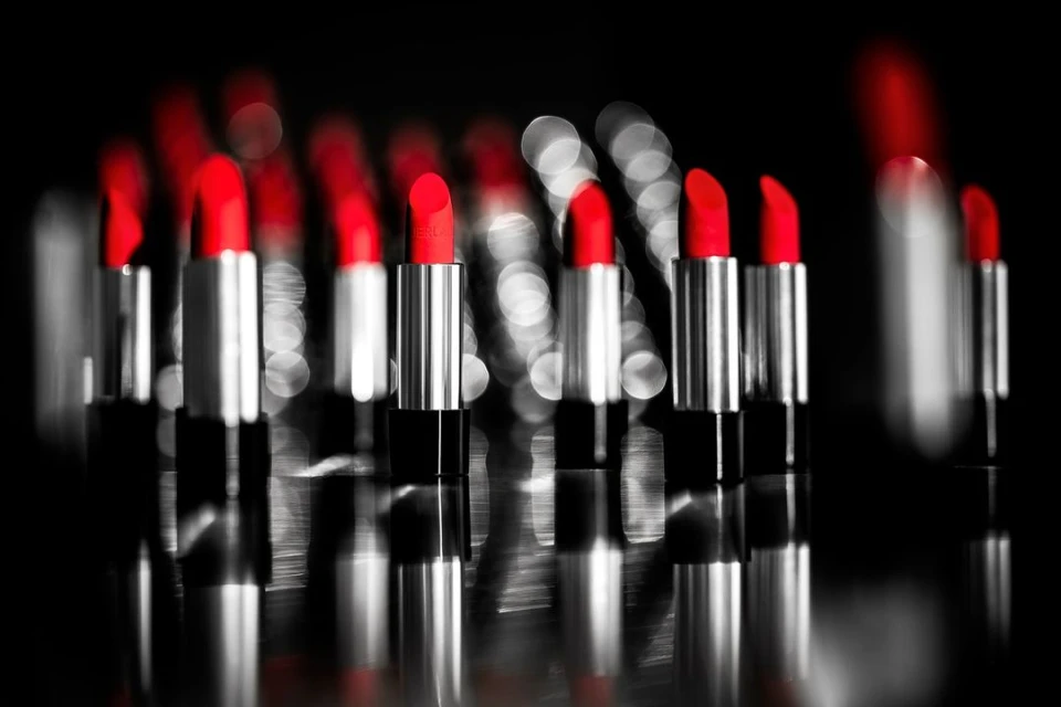 Close-up of multiple silver lipstick tubes with bright red lipstick against blurred background, cosmetic beauty product photography.