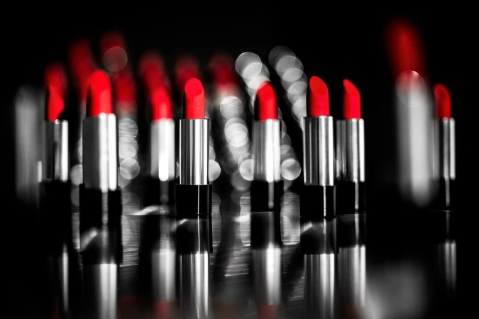 Close-up of multiple silver lipstick tubes with bright red lipstick against blurred background, cosmetic beauty product photography.