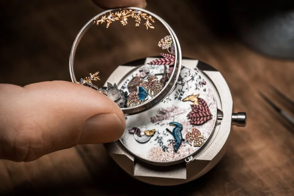 Close-up of watchmaker assembling intricate wristwatch with floral and animal details, showcasing miniature craftsmanship and horology.