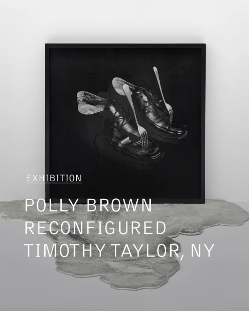 Monochromatic art photography of black leather shoes with forks, set against a black backdrop, displayed in a black frame in a gallery.