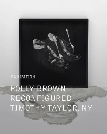Monochromatic art photography of black leather shoes with forks, set against a black backdrop, displayed in a black frame in a gallery.