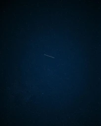 Night sky filled with countless stars and a faint streak of light across the center by photographer Polly Tootal.
