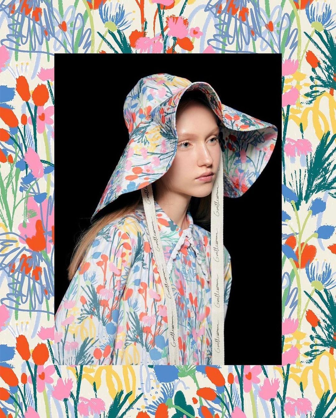 Woman wearing a floral print bucket hat and matching shirt in a close-up studio shot, surrounded by a floral background.