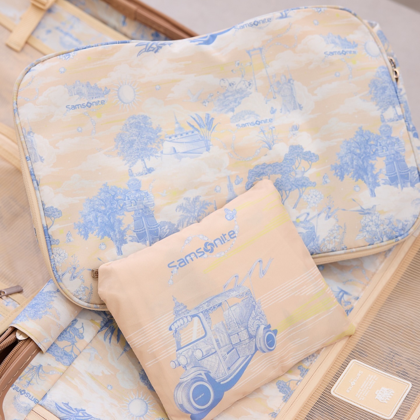 Open suitcase with patterned packing cube and bag featuring a blue tuk-tuk design, ideal for travel-themed visuals.