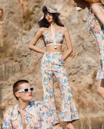 Multiple figures posing outdoors in matching floral print clothing against a rocky mountain backdrop