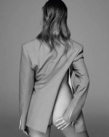 Monochrome portrait of a woman viewed from behind, wearing a tailored blazer backwards with bare back.