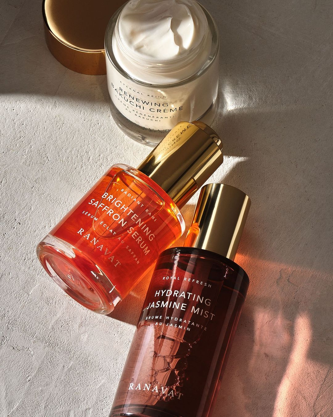 Ranavat skincare product presentation showcasing renewing cream, brightening serum, and hydrating jasmine mist in elegant bottles.