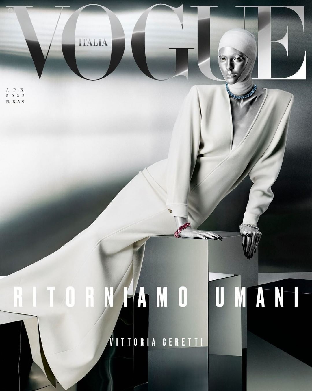 Vogue Italia magazine cover featuring a metallic-skinned mannequin in a white dress, posing on a reflective cube against a silver backdrop.