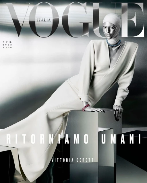 Vogue Italia magazine cover featuring a metallic-skinned mannequin in a white dress, posing on a reflective cube against a silver backdrop.
