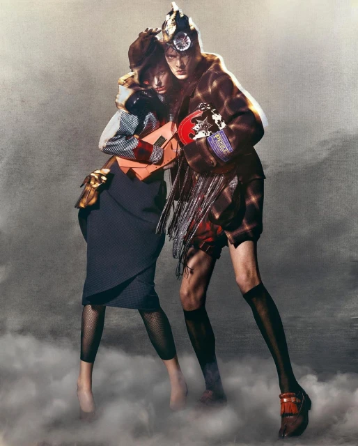 Two fashion models pose in an indoor studio setting with a textured background, showcasing unique clothing, handbags, and footwear.