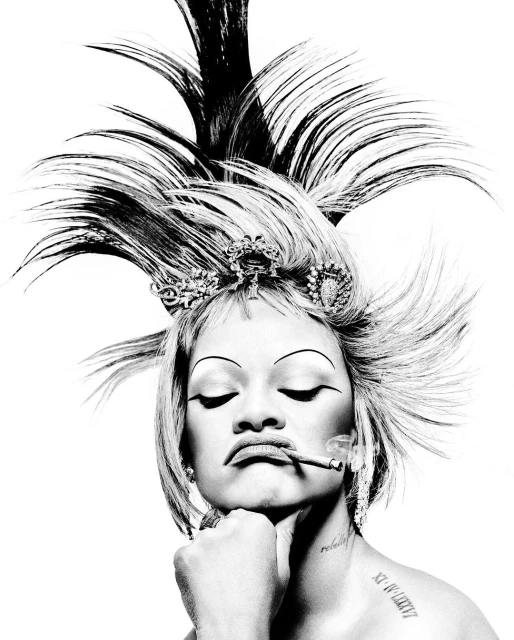 Monochrome portrait of a person with elaborate hairstyle and makeup, smoking a cigarette, set against a stark white background.