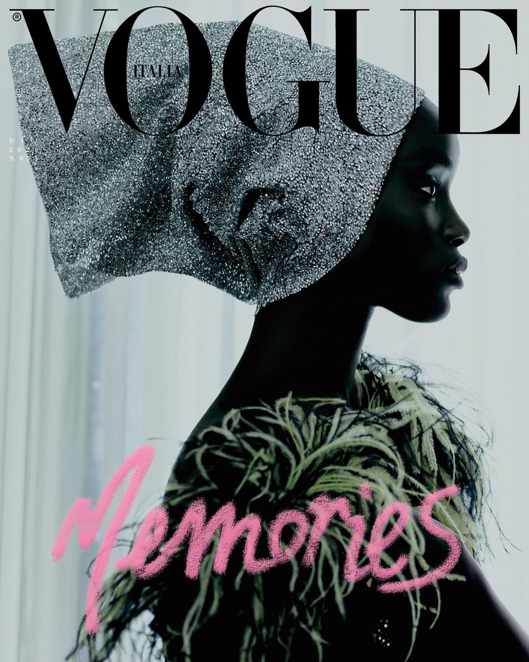 Vogue Italia cover features a Black female model in profile wearing a shimmering head covering and feathered top against a pale background.