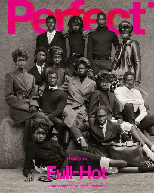 Fashion editorial shot of a group of dark-skinned models in tailored jackets and tops, some seated, in front of a gray background.