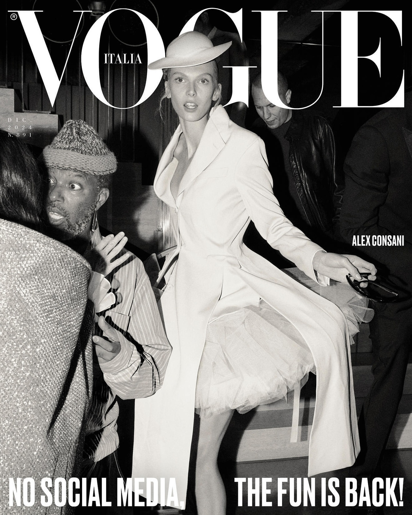 Vogue Italia cover featuring a fashion model in a white coat and hat, surrounded by blurred figures, captured in black and white.