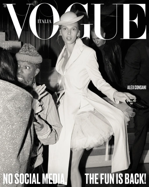 Vogue Italia cover featuring a fashion model in a white coat and hat, surrounded by blurred figures, captured in black and white.