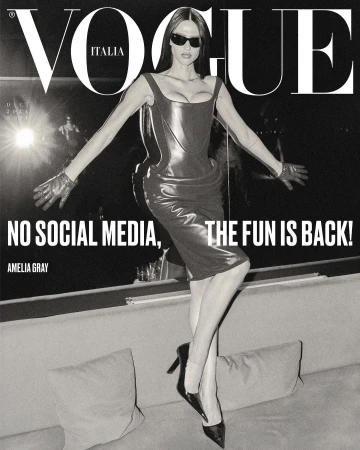 Vogue Italia magazine cover featuring Amelia Gray in a black dress and gloves, striking a pose on a textured couch.