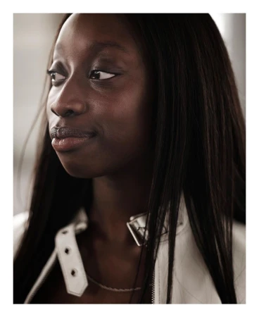 Close-up portrait of a Black woman with long straight dark hair wearing a white jacket by photographer Rahim Fortune.